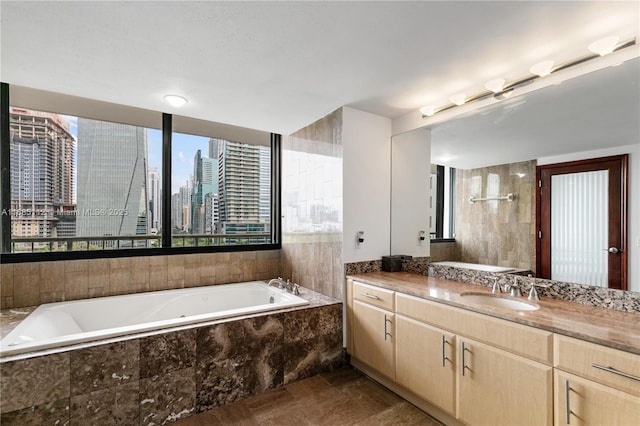 bathroom featuring tiled tub and vanity