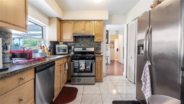 kitchen featuring sink, dark stone countertops, stainless steel appliances, and tasteful backsplash