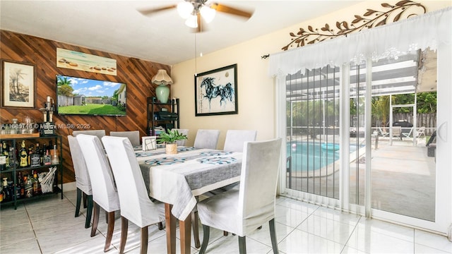 dining space with wooden walls, tile patterned flooring, and ceiling fan