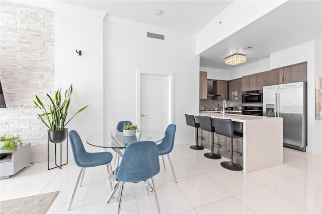 dining space featuring sink, ornamental molding, and light tile patterned floors