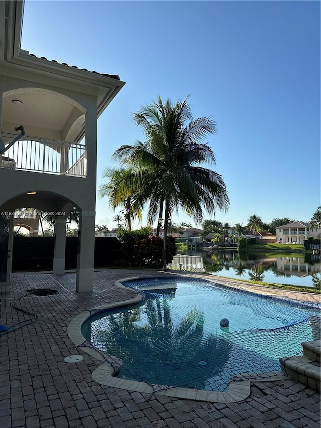 view of pool featuring a water view and a patio