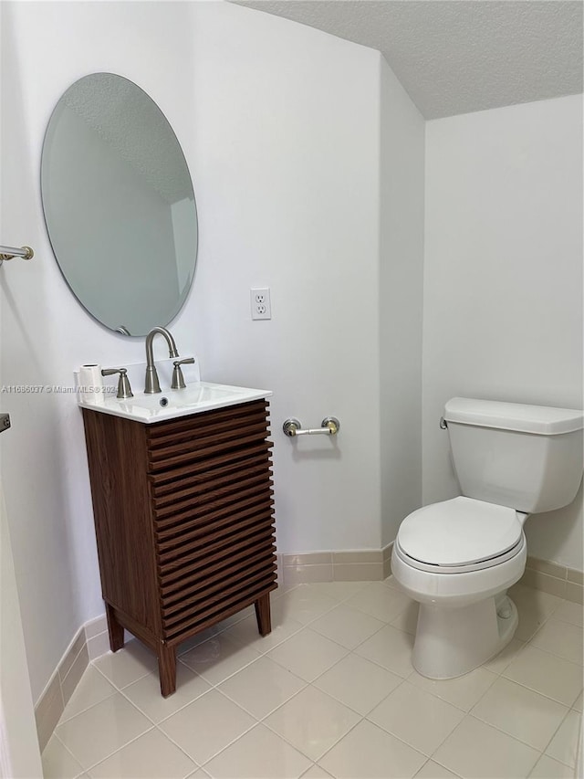 bathroom featuring tile patterned flooring, vanity, a textured ceiling, and toilet