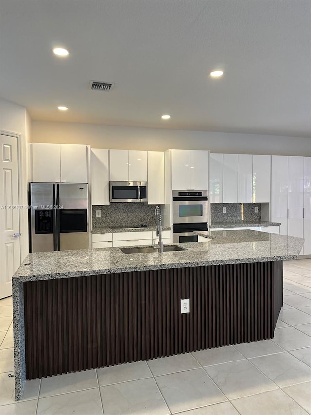 kitchen with white cabinets, sink, decorative backsplash, dark stone countertops, and appliances with stainless steel finishes