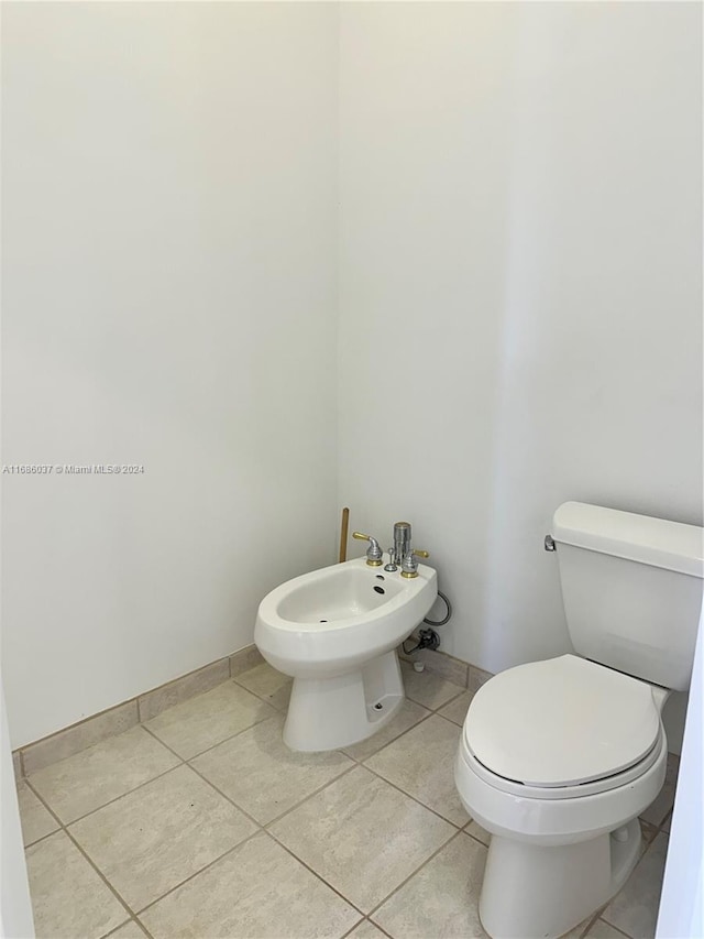 bathroom featuring tile patterned flooring, toilet, and a bidet