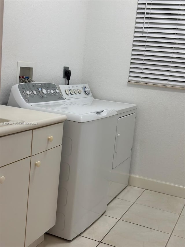 washroom featuring washer and clothes dryer, light tile patterned floors, and cabinets