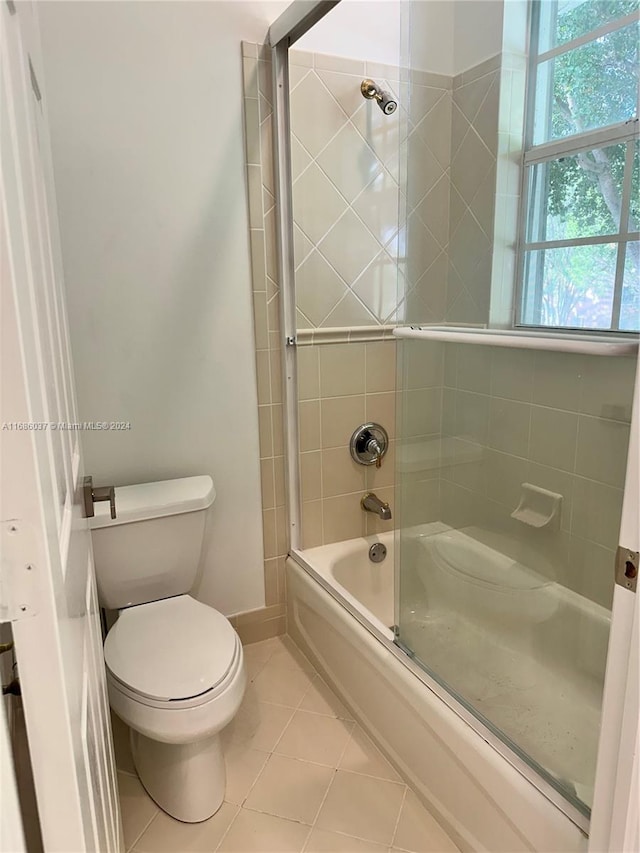 bathroom featuring shower / bath combination with glass door, tile patterned floors, and toilet