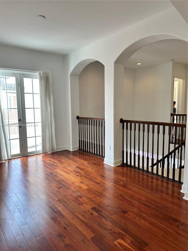 unfurnished room featuring dark hardwood / wood-style flooring, a textured ceiling, and french doors