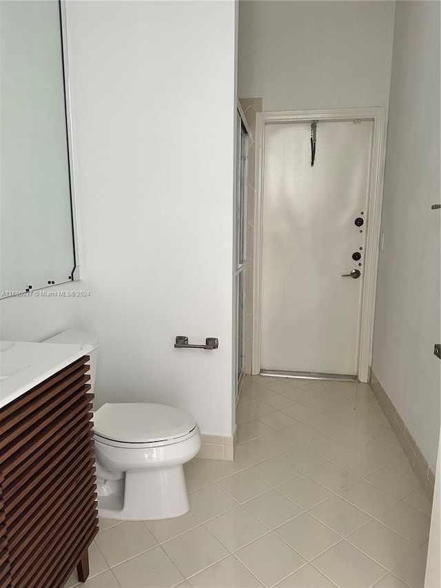 bathroom featuring tile patterned floors, vanity, a shower with shower door, and toilet