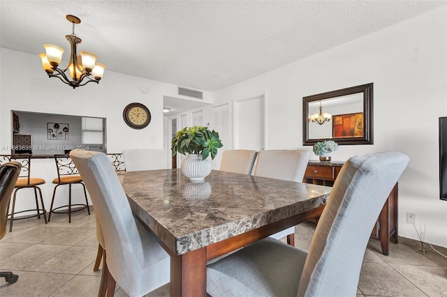 dining space featuring a notable chandelier, a textured ceiling, and light tile patterned floors