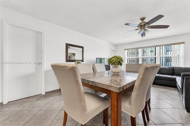 tiled dining area with a textured ceiling and ceiling fan