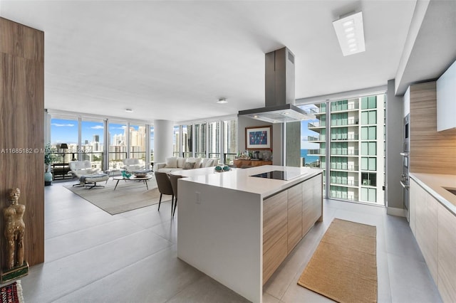 kitchen with island range hood, expansive windows, a center island, and black electric stovetop