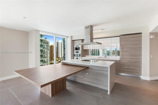 kitchen with island range hood, a center island, white cabinets, and plenty of natural light