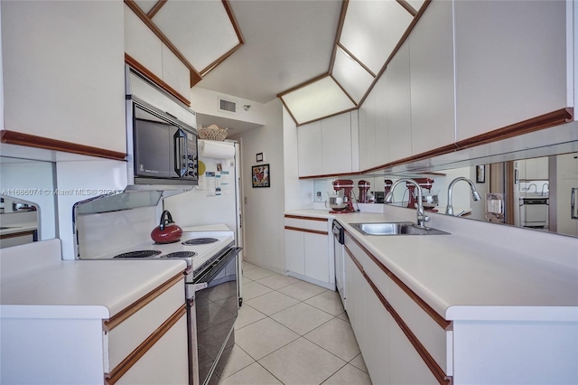 kitchen with light tile patterned floors, white appliances, white cabinetry, and sink