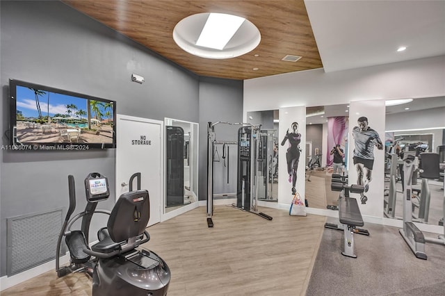 exercise room with wood ceiling, wood-type flooring, and a high ceiling