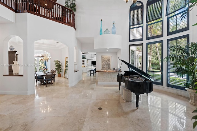 entryway with a towering ceiling, an inviting chandelier, and crown molding