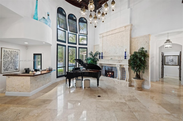 miscellaneous room featuring a high ceiling, a notable chandelier, and a premium fireplace