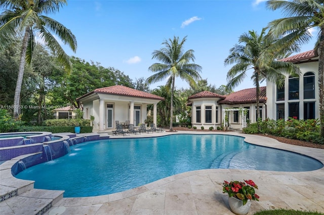 view of pool featuring an in ground hot tub, pool water feature, and a patio