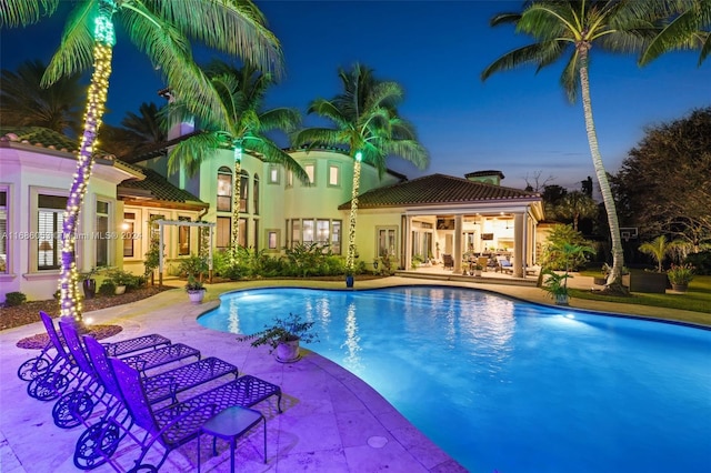 pool at dusk featuring a patio