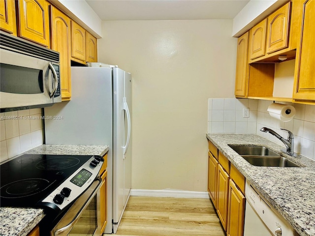 kitchen with decorative backsplash, light stone countertops, light wood-type flooring, sink, and stainless steel appliances