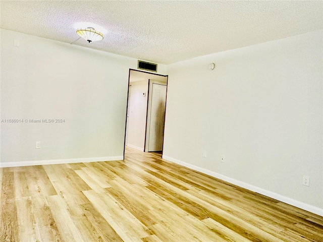 unfurnished room featuring light hardwood / wood-style floors and a textured ceiling