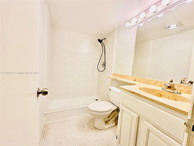 bathroom with vanity, toilet, tile patterned floors, and tiled shower