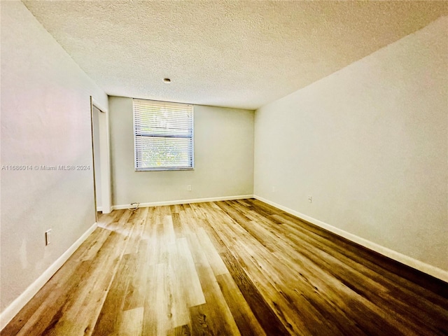 unfurnished room featuring hardwood / wood-style floors and a textured ceiling