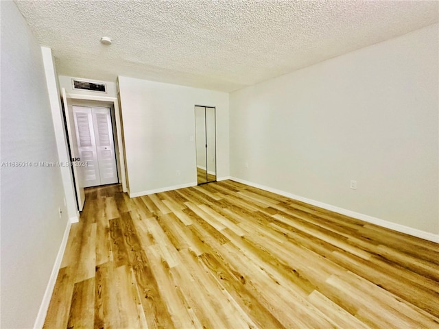 spare room featuring a textured ceiling and light hardwood / wood-style flooring