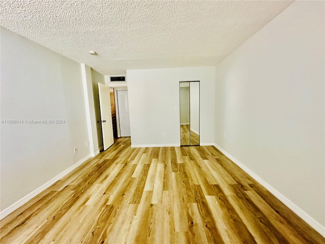 unfurnished bedroom with a textured ceiling and light hardwood / wood-style flooring