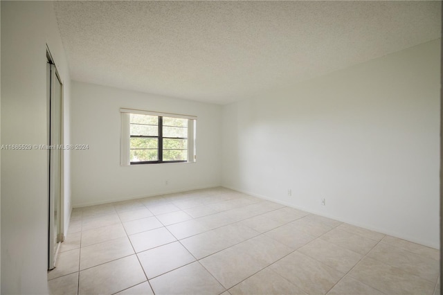 tiled spare room featuring a textured ceiling