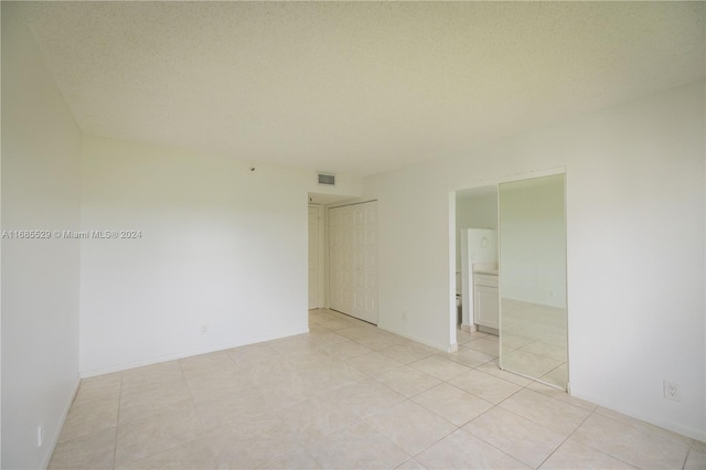 spare room with a textured ceiling and light tile patterned floors