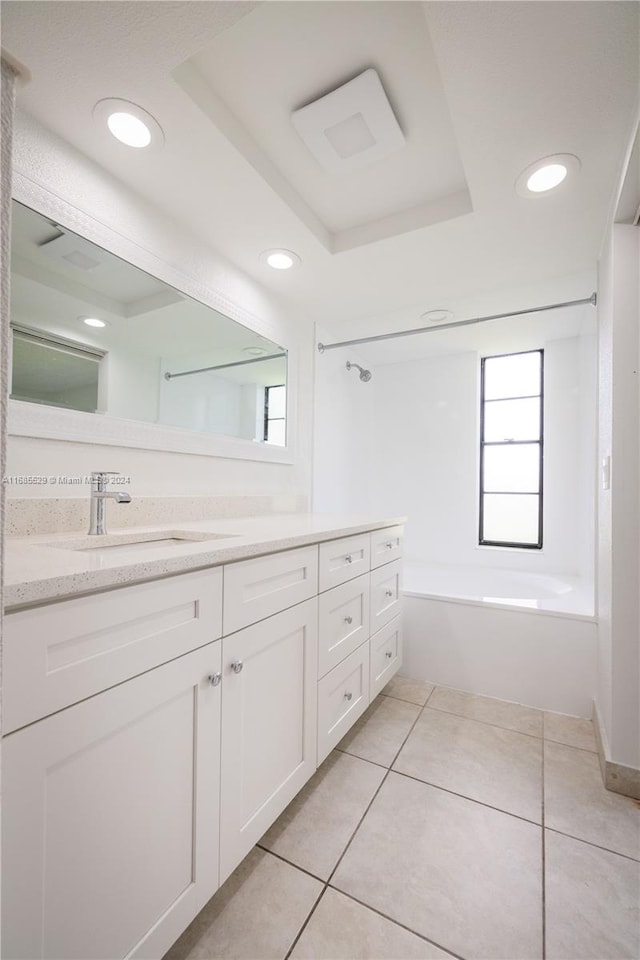 bathroom featuring a tray ceiling, vanity, tile patterned flooring, and bathing tub / shower combination