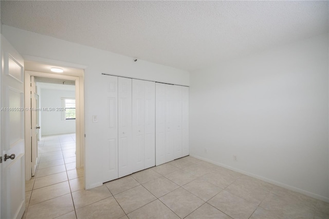 unfurnished bedroom with light tile patterned flooring, a textured ceiling, and a closet