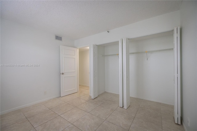 unfurnished bedroom with a textured ceiling and light tile patterned floors