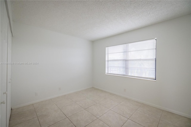 tiled empty room with a textured ceiling