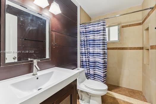 bathroom with toilet, vanity, and a shower with shower curtain