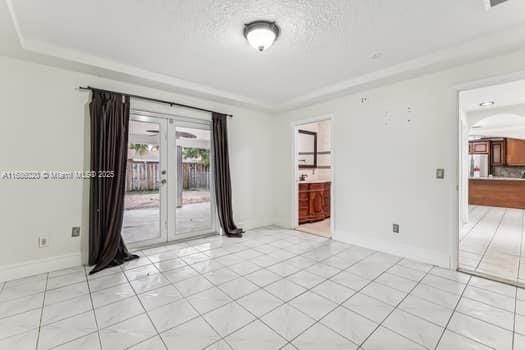 spare room with french doors, a tray ceiling, and a textured ceiling