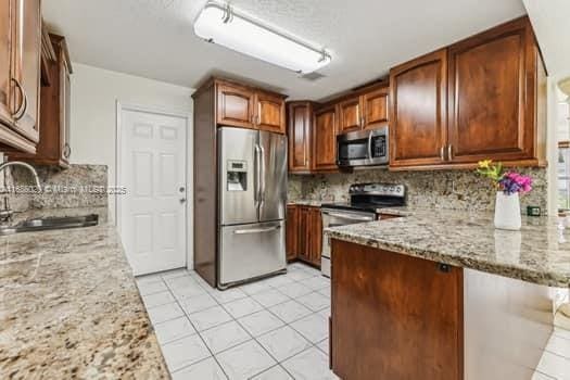 kitchen featuring light stone countertops, appliances with stainless steel finishes, sink, and tasteful backsplash