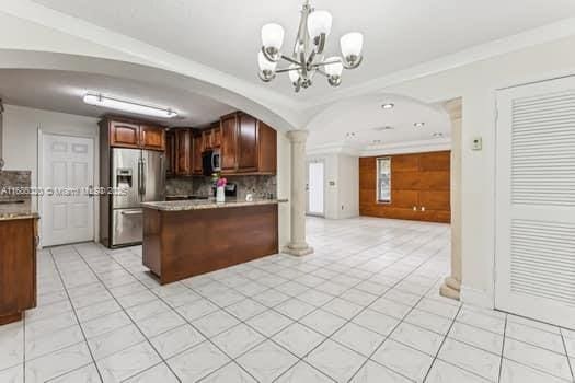 kitchen featuring tasteful backsplash, kitchen peninsula, hanging light fixtures, appliances with stainless steel finishes, and a chandelier