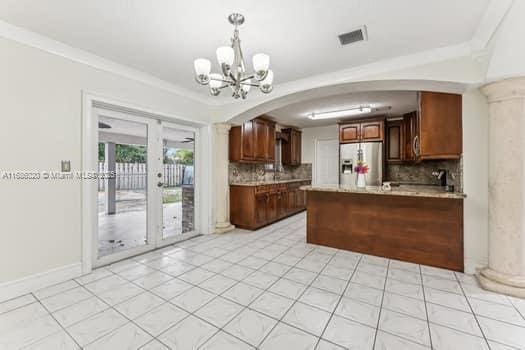 kitchen with kitchen peninsula, french doors, stainless steel fridge with ice dispenser, and decorative backsplash