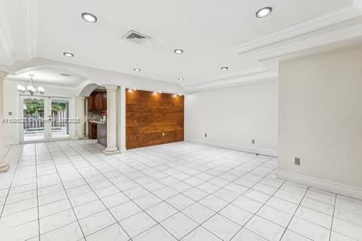 spare room featuring light tile patterned floors, ornate columns, and french doors