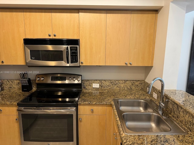 kitchen with dark stone countertops, stainless steel appliances, and sink