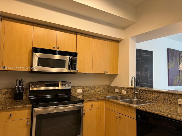 kitchen featuring dark stone countertops, appliances with stainless steel finishes, and sink