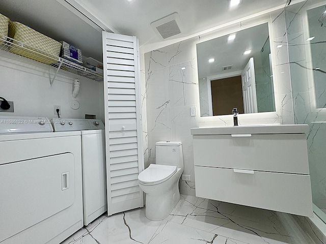 bathroom featuring vanity, washer and dryer, and toilet