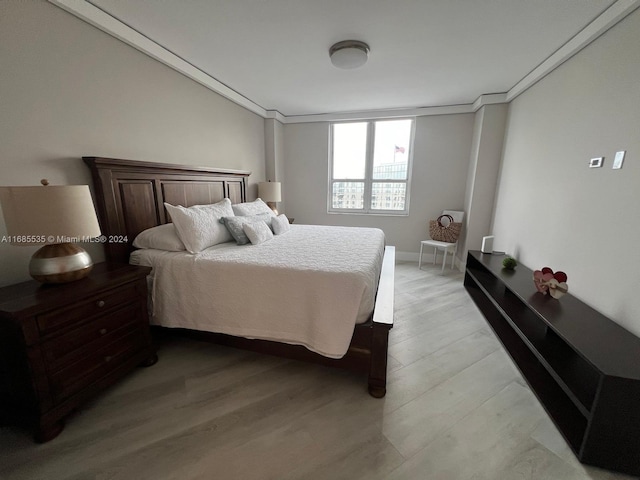 bedroom with crown molding and light wood-type flooring