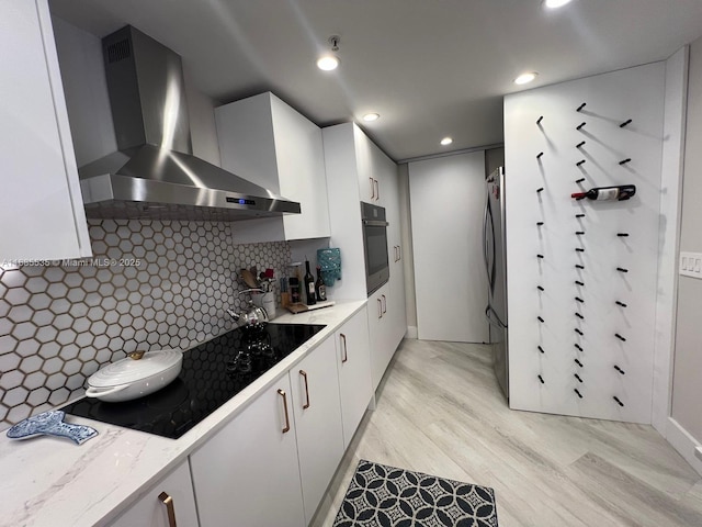 kitchen with decorative backsplash, kitchen peninsula, pendant lighting, white cabinetry, and light hardwood / wood-style floors