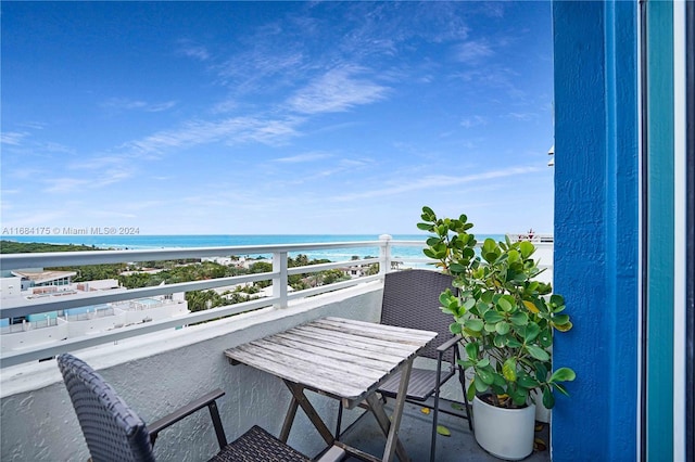 balcony with a water view and a view of the beach