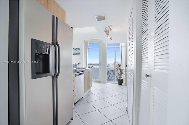 kitchen with stainless steel appliances, floor to ceiling windows, sink, and light tile patterned floors