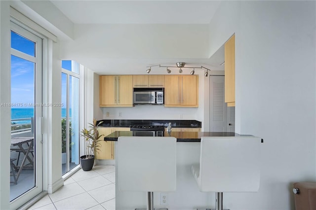 kitchen with stainless steel appliances, a water view, and light tile patterned floors