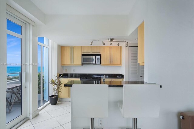 kitchen with stove, light tile patterned floors, plenty of natural light, and a water view