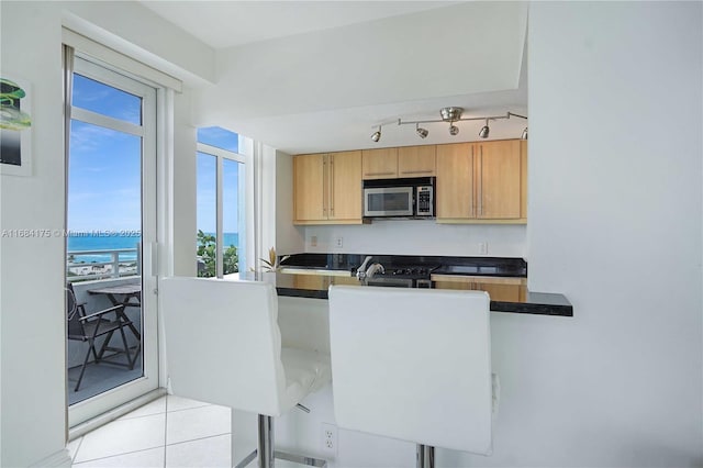 kitchen with light tile patterned flooring, a water view, and sink